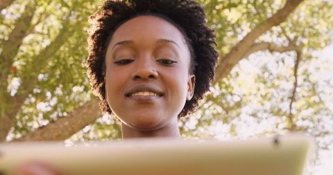Woman Enjoying Tablet in Park on Sunny Day