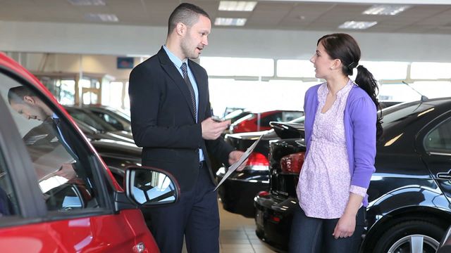 Salesperson displaying new car options to potential customer. Ideal for illustrating automotive dealership, customer service, and sales interaction scenarios. Useful for websites or advertisements focusing on car buying, customer service tips, and automotive industry guides.