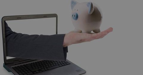 Extending suited arm holding piggy bank from laptop screen symbolizing digital savings
