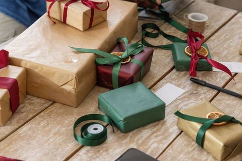 Hands tying green ribbon on kraft gift with dried orange slice decorations