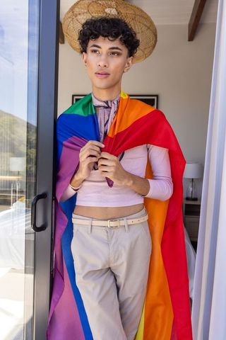 Person Embracing Rainbow Flag in Modern Balcony Doorway Setting
