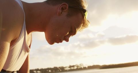 Focused male rower by river preparing boat at sunrise