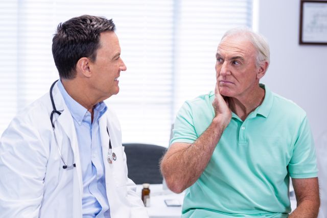 Senior man showing neck pain to doctor in clinic