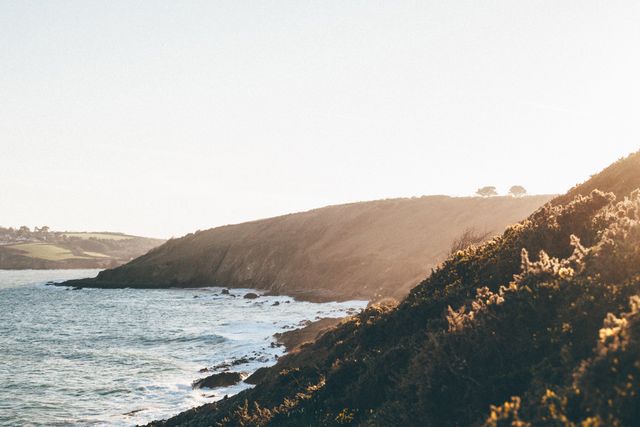 Sunlit Coastal Landscape with Rolling Hills and Ocean Waves - Download Free Stock Images Pikwizard.com