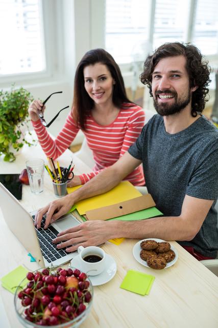 Male and female graphic designers using laptop in office