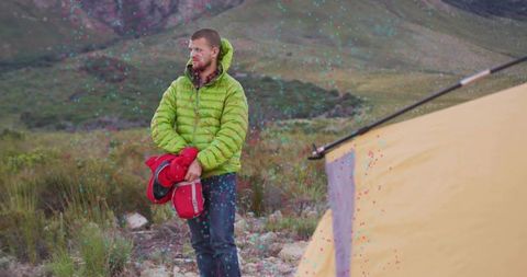 Camper in Green Jacket Holding Red Mat Near Mountain Tent