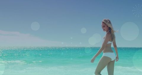 Carefree Woman Strolling on Sunny Beach with Bokeh Effects
