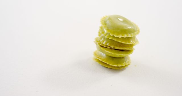 Stacked green spinach ravioli pasta isolated on a white background, with copy space. The arrangement highlights the simplicity and appeal of Italian cuisine.