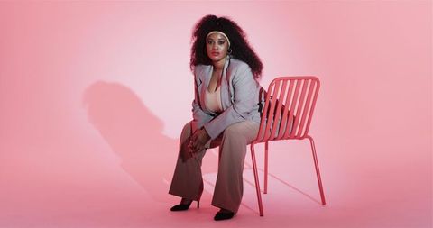 Elegant Professional Woman Sitting in Pink Studio