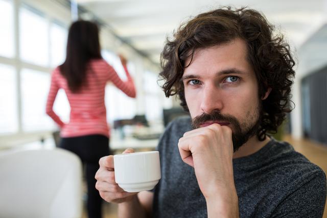 Portrait of male graphic designer holding a cup of coffee in office