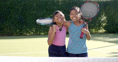 Two Smiling Girls Enjoying Tennis on Sunny Day