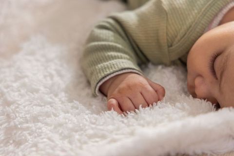 Infant sleeping on plush shaggy blanket wearing mint ribbed long-sleeve top, closeup
