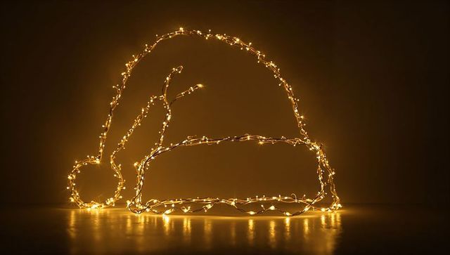 Glowing santa hat outline made with warm led string lights casting reflection