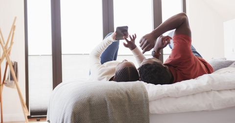 Couple Relaxing With Smartphone in Cozy Bedroom