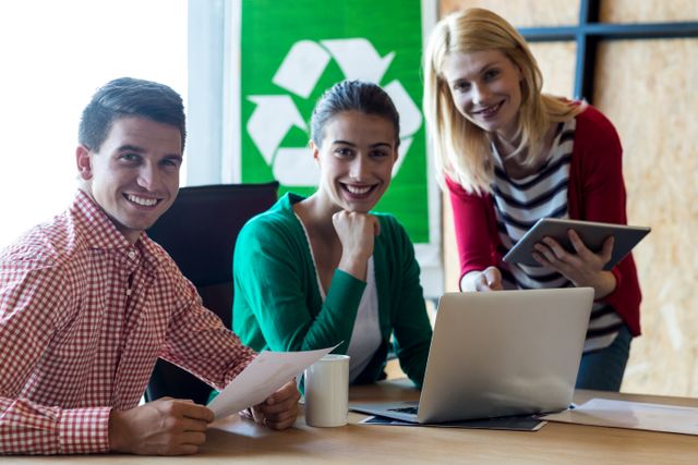 Group of colleagues discussing eco-friendly initiatives in an office setting. Ideal for use in articles, blogs, and presentations about teamwork, sustainability, and green business practices.