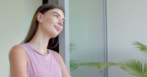 Young Woman Smiling Looking Out Window in Pink Top