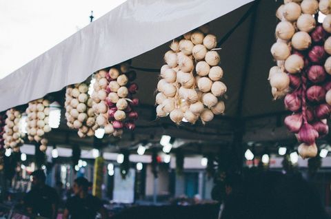 Bundles of garlic and onions hanging at outdoor market stall