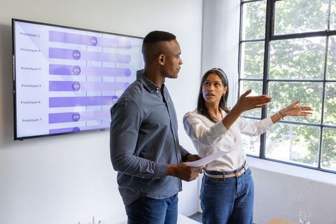 Diverse coworkers presenting data and discussing analytics in modern office meeting