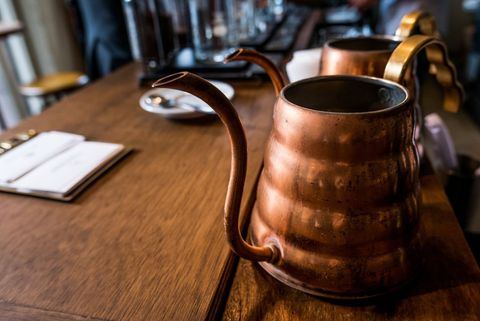 Copper kettles on rustic wooden table in café