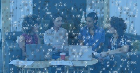 Diverse team collaborating over laptops with binary code overlay for digital brainstorming