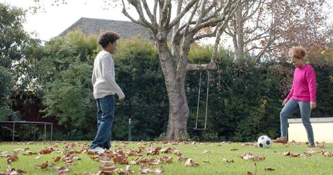 Mother and Son Playing Soccer in Leafy Garden - Download Free Stock Images Pikwizard.com
