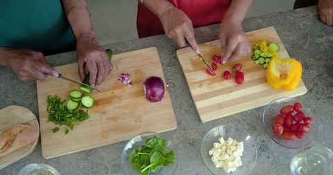 African american women chopping fresh vegetables together for healthy salad prep