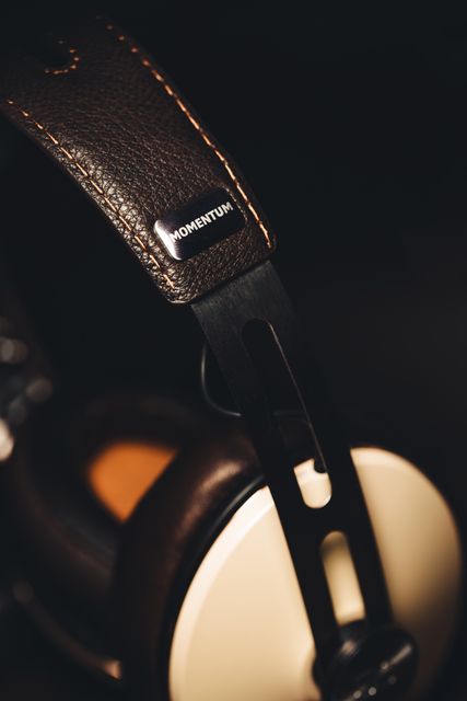 Close-up detail of luxurious leather over-ear headphones highlighted against a dark background. Great for promotions focused on high-end audio equipment, tech blogs, and product reviews. Perfect for advertising premium headphones or illustrating blog posts about music, gaming, or technology gadgets.