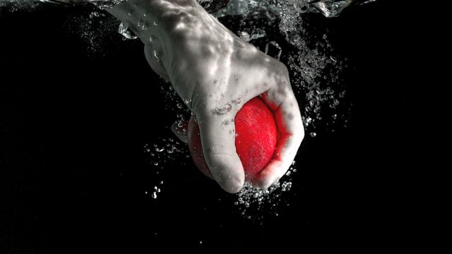 This photo depicts a hand reaching into water to seize a red apple, highlighting the motion with a dramatic underwater splash effect. Splash and bubbles enhance the feeling of freshness and dynamism. Useful for advertising themes focusing on purity, health, and vitality, such as nutrient-rich beverages or fresh produce promotions.