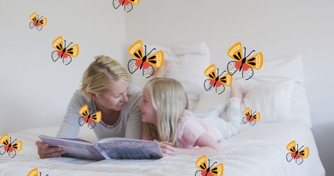 Happy Mother and Daughter Reading in Bed Surrounded by Butterflies