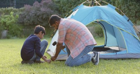Father and son building tent outdoors during bonding time
