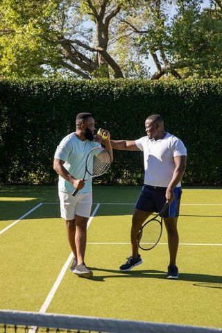 Friends Enjoying Tennis Match and Staying Hydrated on Sunny Day