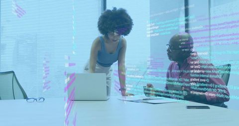 Woman and senior colleague collaborating on software development in modern boardroom