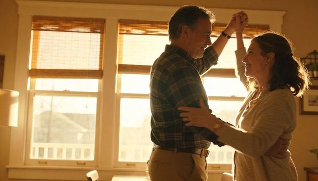 Middle-aged couple dancing in sunlit living room at golden hour, embracing warm moment