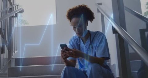 Nurse receiving emergency alert on smartphone while checking ecg signal on stairwell
