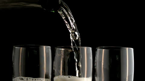Pouring Champagne into Flutes with Black Background