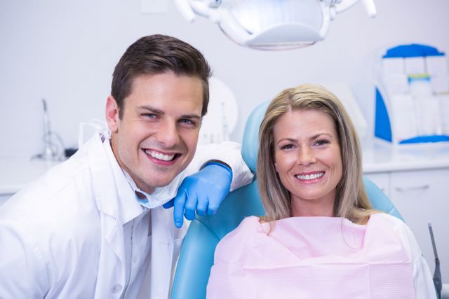 Dentist and patient smiling in dental clinic. Ideal for use in healthcare, dental care, and medical service promotions. Can be used in brochures, websites, and advertisements for dental clinics and oral health services.