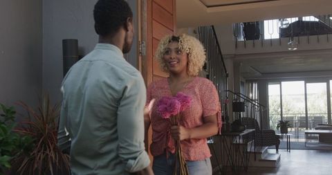 Woman Holding Flowers Greeting Friend at Home with Cheerful Smile