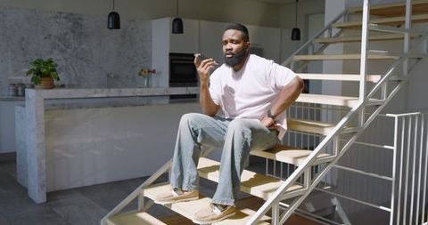 Man on Staircase Communicating via Smartphone in Modern Kitchen
