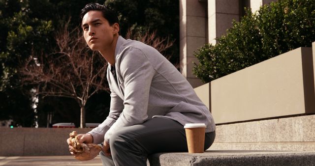 Young Man Enjoying Break Sitting Outdoors with Coffee and Snack - Download Free Stock Images Pikwizard.com