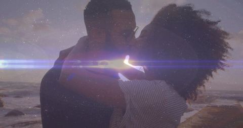 Romantic Couple Embracing at Sunset by Rocky Shoreline