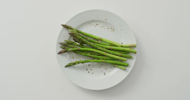 Image of fresh asparagus stalks on white plate over white background. fusion food, fresh vegetables and healthy eating concept.