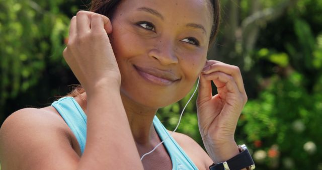 Smiling Woman Outdoors Putting on Earphones during Exercise - Download Free Stock Images Pikwizard.com