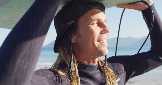 Surfer with long braided hair holding surfboard on sunny beach - Download Free Stock Images Pikwizard.com