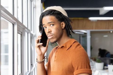 Young african american professional making phone call by window in modern coworking space