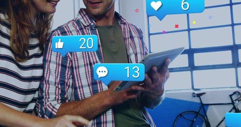 Couple interacting on tablet with floating social media notifications in creative workspace