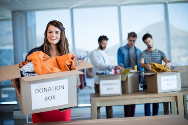 Portrait of smiling woman holding a donation box in office
