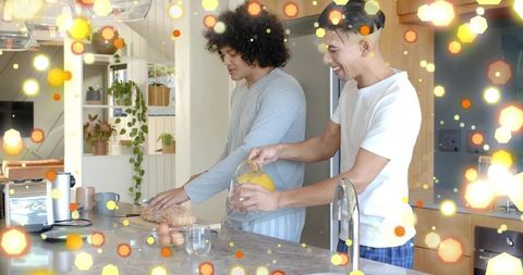 Two men preparing cozy morning breakfast pouring orange juice and slicing bread at island