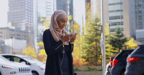 Woman in Hijab Using Smartphone on City Street