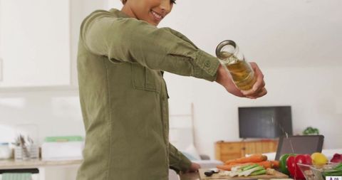 Woman Pouring Oil on Vegetables in Contemporary Home Kitchen