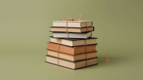 Stack of vintage hardcover books tied with twine on olive-green backdrop